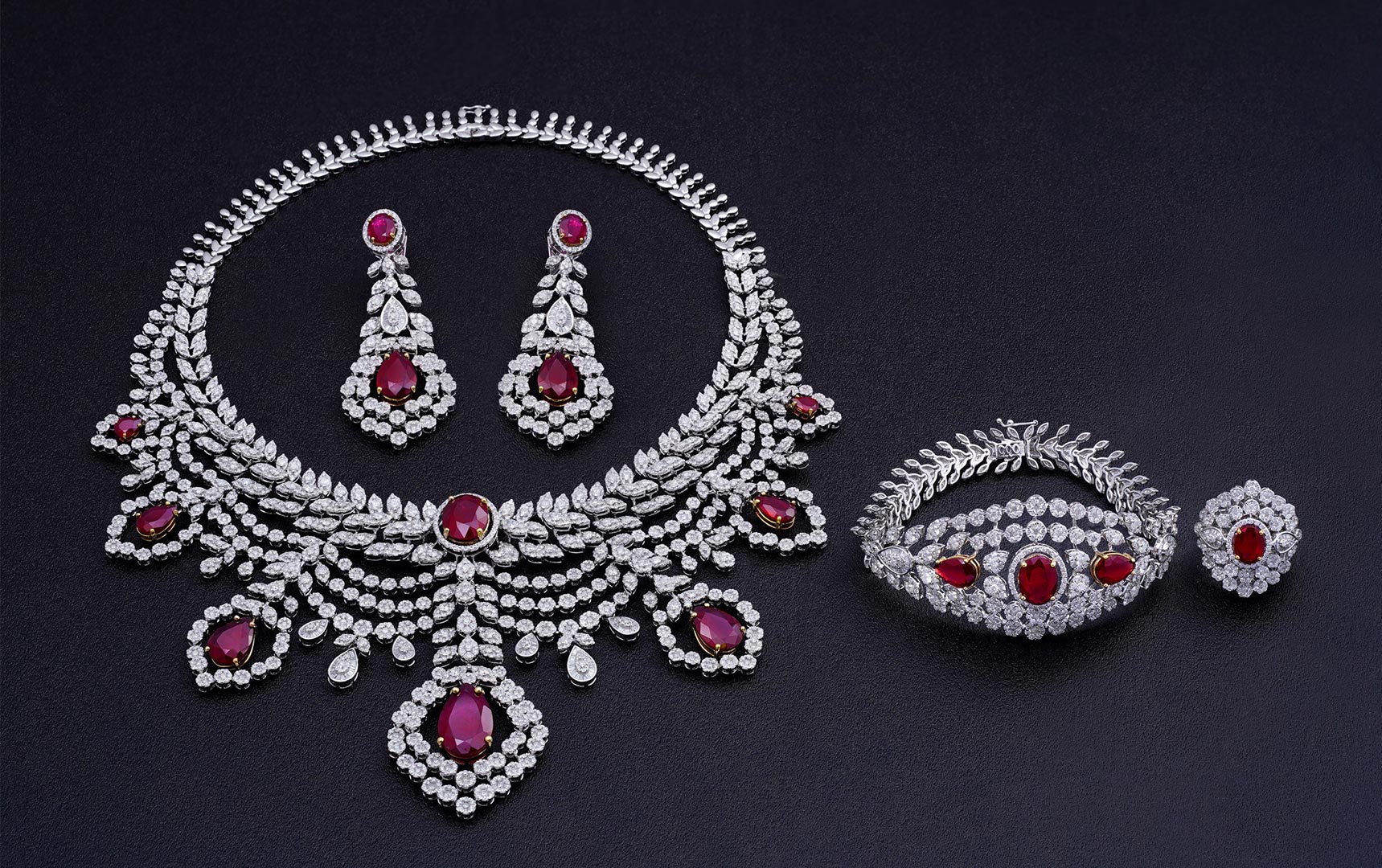 A diamond jewelry set with necklace, earrings, ring, and bracelet/bangle displayed together